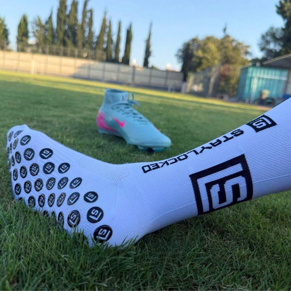 StayLocked® anti-slip grip socks close-up showing rubber grip dots on football pitch